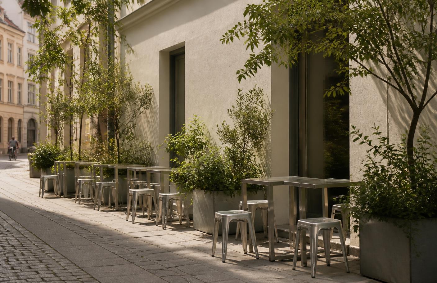 Plant-filled outdoor seating with aluminum stools on the street outside ORNO Café